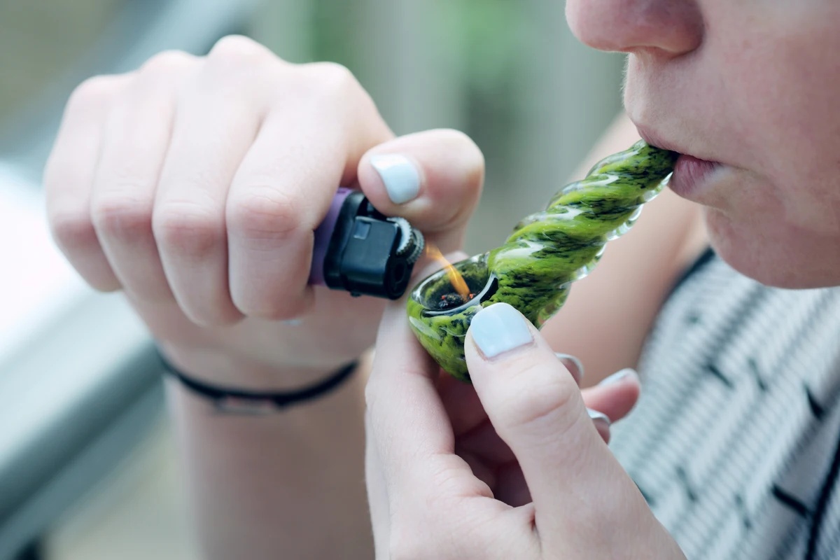 Marijuana Addiction: Woman smoking marijuana out of a pipe