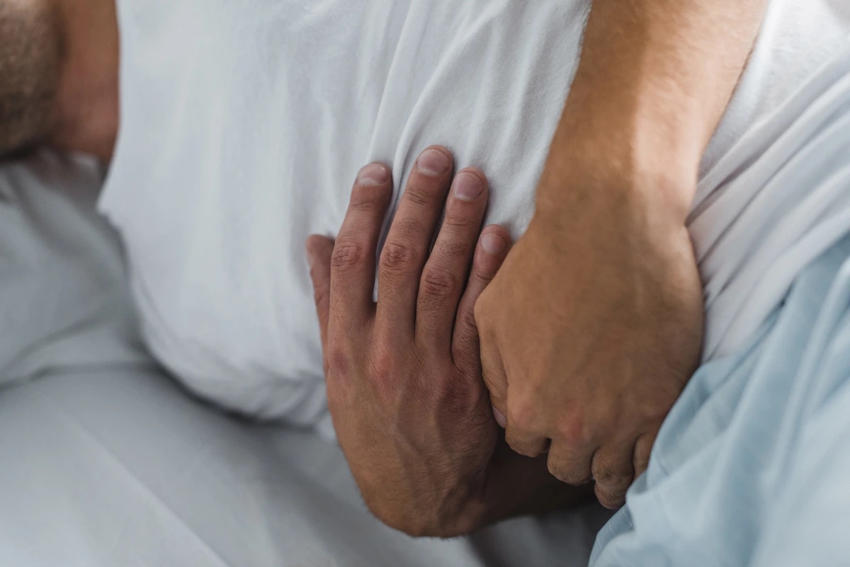 Drug Detox: Man in bed holding his stomach uncomfortably
