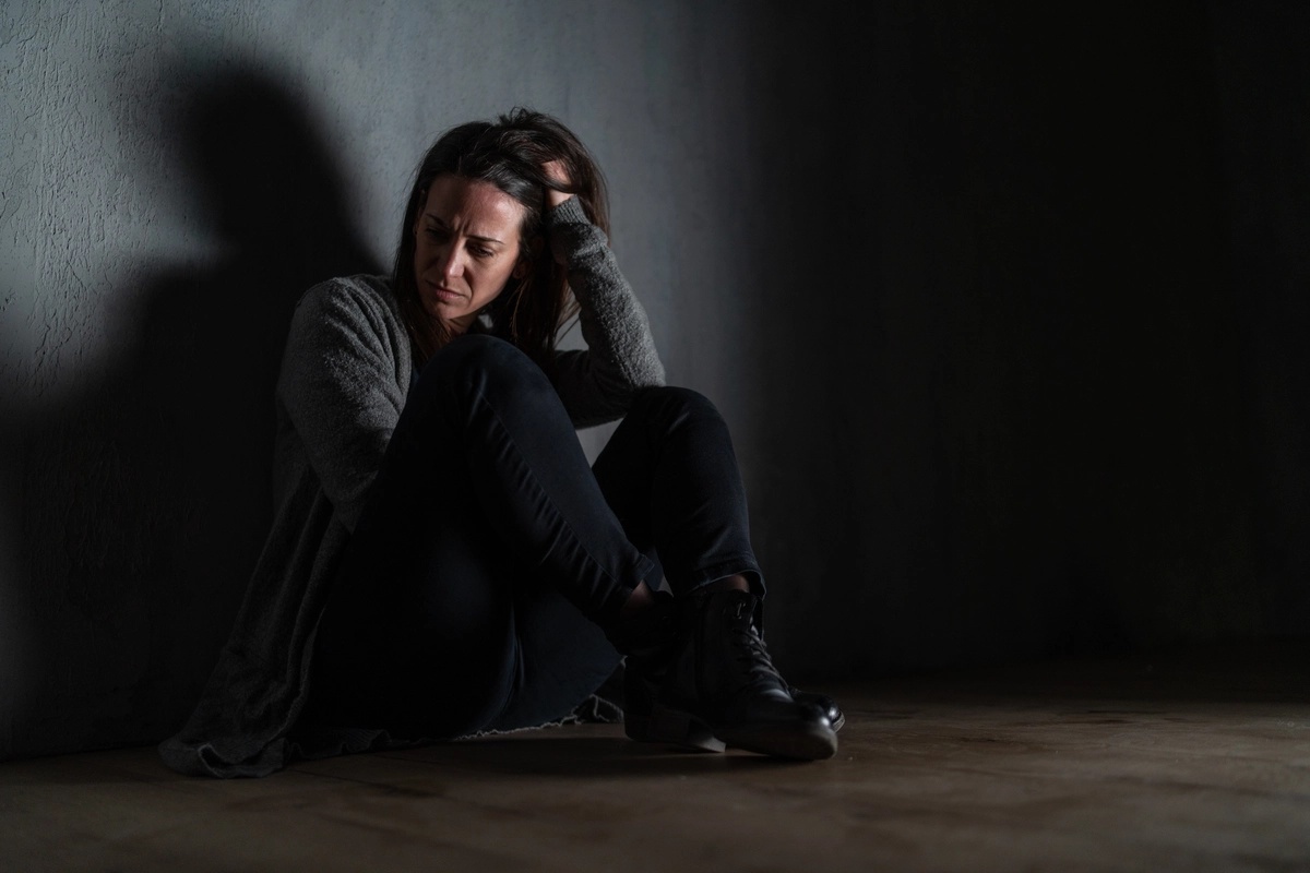 Inhalant Addiction: Woman sitting in the dark against a wall